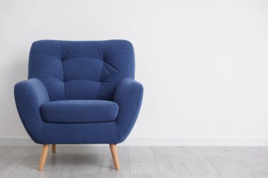 Beyaz duvarın yanındaki rahat mavi koltuk, metin için boşluk.