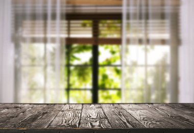 Odasında perdeler olan pencereye karşı boş ahşap masa