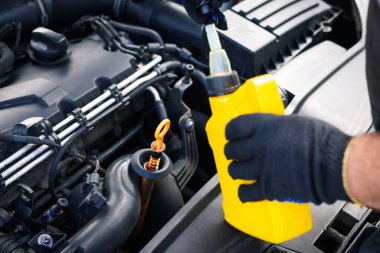 İşçi arabada motor yağı seviyesini dipstick ile kontrol ediyor.