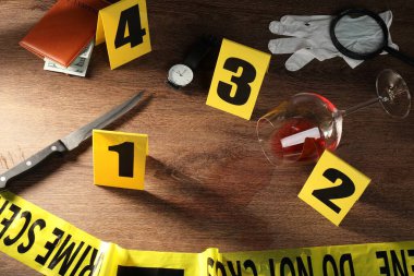 Adli tıp uzmanı. Sarı olay yeri bandı, ahşap masada işaretler ve kanıtlar var.