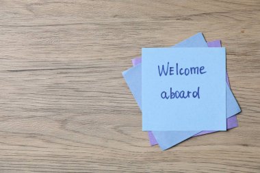 Tahta masaya hoş geldiniz cümlesinin yazılı olduğu kağıt not, üst manzara. Metin için boşluk