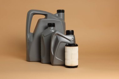 Plastik kutularda motor yağı ve bej arka planda filtre, metin için boşluk