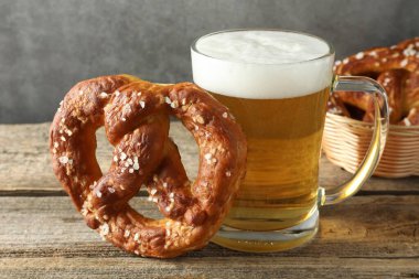 Lezzetli kraker ve bir bardak bira ahşap masada, gri arka planda, yakın planda.