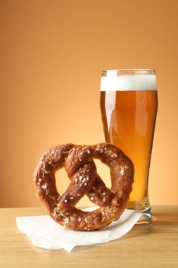 Lezzetli kraker ve bir bardak bira ahşap masada bej renkli arka planda, yakın plan.