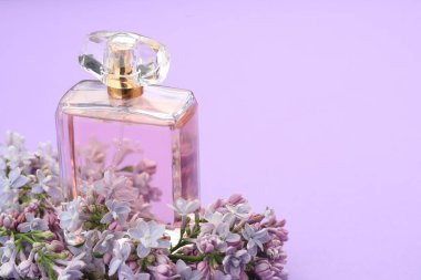 Parfüm şişesi ve mor arka planda leylak çiçekleri, yakın plan. Metin için boşluk