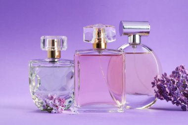 Parfümlü şişeler ve mor arkaplanda leylak çiçekleri, yakın plan.