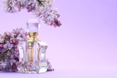 Parfüm şişesi ve mor arkaplanda leylak çiçekleri, yakın plan. Metin için boşluk