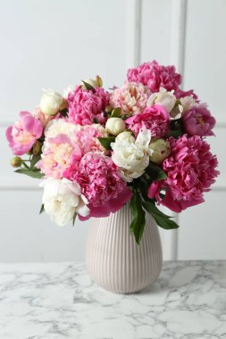 İçerideki beyaz mermer masada vazodaki güzel şakayıklar.