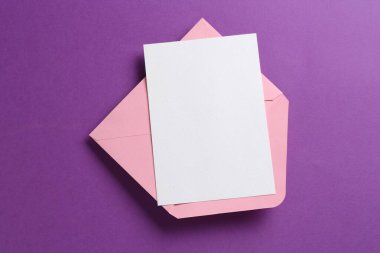 Mor arka planda boş davetiye ve zarf, üst manzara. Tasarım için boşluk