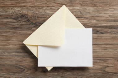 Boş davetiye kartı ve zarf ahşap masanın üstünde, üst tarafta. Tasarım için boşluk
