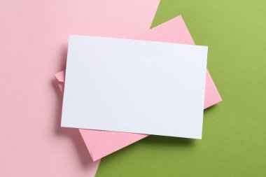 Renk arkaplan üzerinde boş davetiye ve zarf, üst görünüm. Tasarım için boşluk