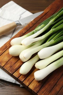 Taze taze soğanlar, ahşap masada kesme tahtası ve bıçakla yakın plan.