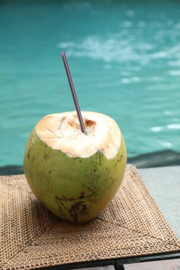 Yeşil hindistan cevizi, ferahlatıcı bir içecek ve hasır üzerinde hasır yüzme havuzu yakınında, yakın plan.