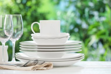 Bulanık yeşil arka planda beyaz masada farklı temiz tabaklar