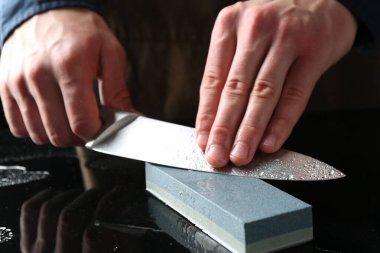 Ayna masasında bileyiciyle bileyen adam, yakın plan.