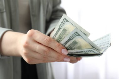 Kadın içeride dolar sayıyor, yakın çekim manzarası var.