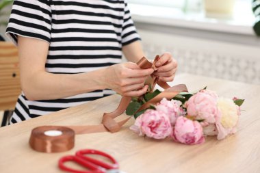 Çiçekçinin ahşap masasında şakayık buketi yapan çiçekçi, yakın plan.