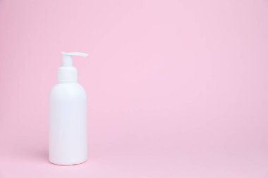 Pembe arka planda beyaz bir kozmetik ürünü şişesi, metin için boşluk