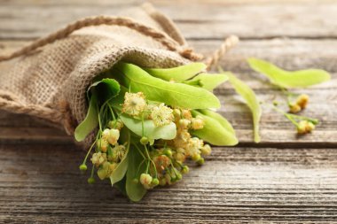 Güzel ıhlamur çiçekleri ve yapraklar çuval içinde ahşap masada, yakın plan