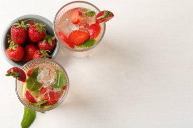 Beyaz masada çilekli, limonlu ve nane şekerli, ferahlatıcı bir içecek. Metin için boşluk