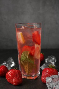 Koyu arkaplan üzerinde çilek ve buzla serinletici içecek, yakın plan.