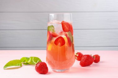 Çilekli içecek, nane ve buz pembe ahşap masada gri arka planda, yakın plan