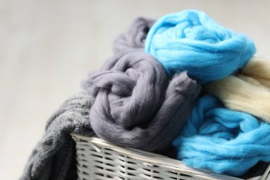 Açık gri arka planda hasır sepetteki yumuşak yün, yakın plan
