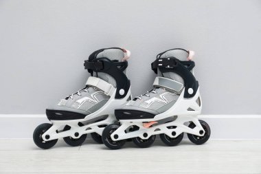 Beyaz duvarın yanında yerde bir çift paten var.