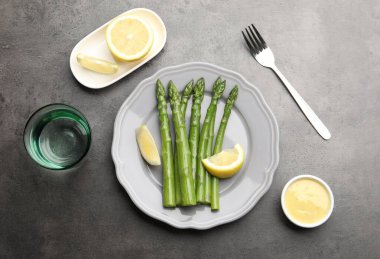 Gri masada limonla servis edilen lezzetli pişmiş kuşkonmaz.