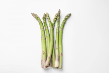 Beyaz arka planda taze taze çiğ kuşkonmaz, düz yatıyordu.