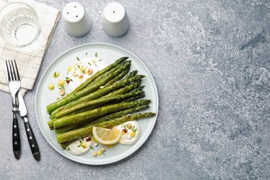 Lezzetli pişmiş kuşkonmaz, limon ve sosla servis edilmiş gri masa, düz yatak. Metin için boşluk