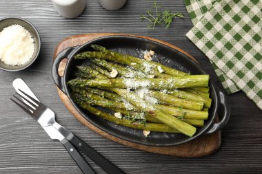 Siyah ahşap masada parmesanla servis edilen lezzetli pişmiş kuşkonmaz.