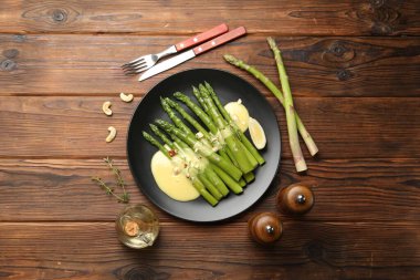 Ahşap masada sosla servis edilen lezzetli pişmiş kuşkonmaz.