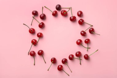 Pembe arka planda taze olgun kiraz çerçevesi, düz. Metin için boşluk