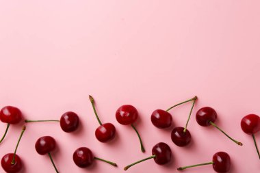 Pembe arka planda taze kirazlar, düz uzanmış. Metin için boşluk
