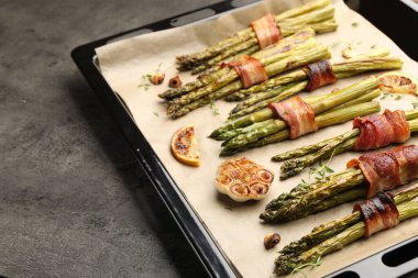 Pastırmalı ve baharatlı kuşkonmaz pişirilmiş. Gri masada, yakın plan. Metin için boşluk