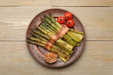 Ahşap masada domuz pastırması ve baharatla servis edilen lezzetli kuşkonmaz.