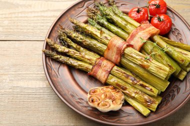 Ahşap masada domuz pastırması ile servis edilen lezzetli kuşkonmaz, yakın plan.