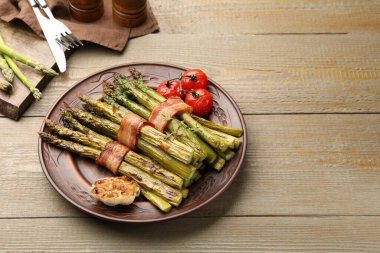Ahşap masada domuz pastırması ve baharatla servis edilen lezzetli pişmiş kuşkonmaz. Metin için boşluk