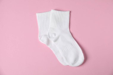 Pembe arka planda bir çift rahat beyaz çorap, üst manzara