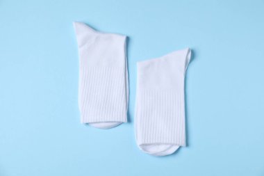 Açık mavi arka planda bir çift rahat beyaz çorap, üst manzara