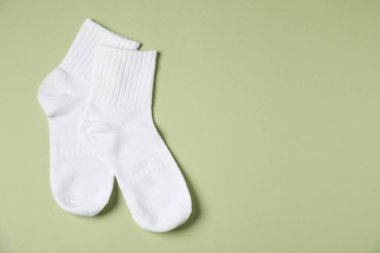 Açık yeşil arka planda bir çift rahat beyaz çorap, üst manzara. Metin için boşluk