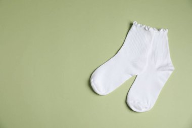 Açık yeşil arka planda bir çift rahat beyaz çorap, üst manzara. Metin için boşluk
