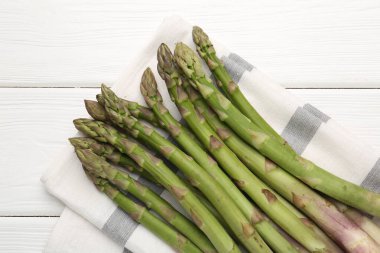 Beyaz ahşap masada taze çiğ kuşkonmaz mızrakları.