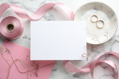 Düğün davetiyesi, altın yüzükler, kurdele, zarf ve dallar beyaz mermer masa, düz yatıyordu.