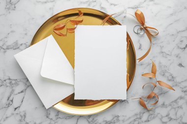 Düğün davetiyesi, altın tepsi, yüzükler, zarf ve dal beyaz mermer masa üzerinde kuru yapraklar, düz yatıyordu