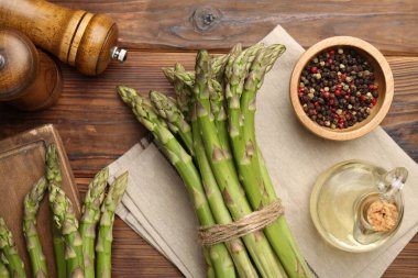 Taze çiğ kuşkonmaz, baharat ve yağ ahşap masada, düz yerde.