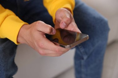 Ergen çocuk evde akıllı telefon kullanıyor, yakın plan.