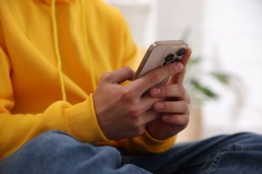 Ergen çocuk evde akıllı telefon kullanıyor, yakın plan.