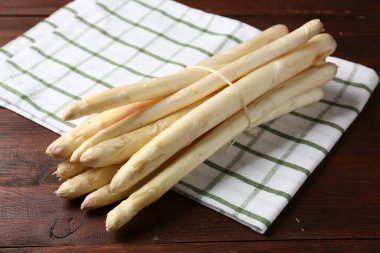 Ahşap masada çiğ kuşkonmaz mızrakları, yakın plan.